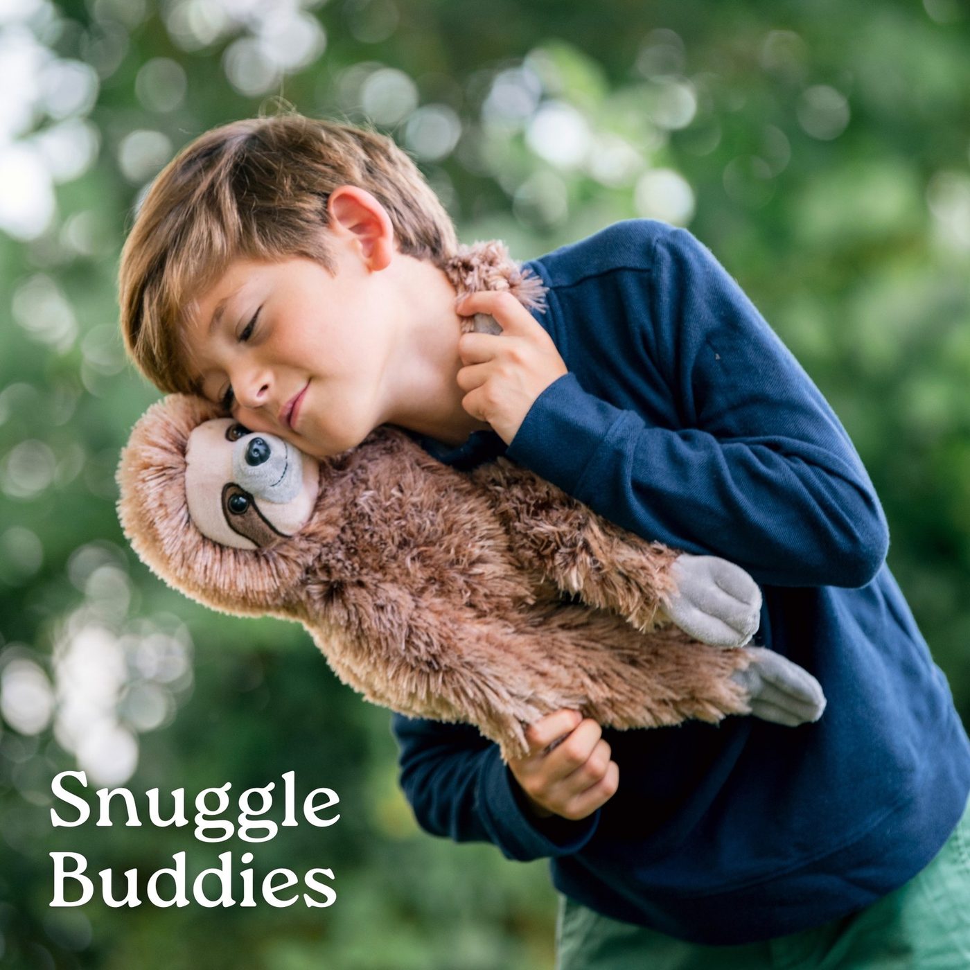 A boy in a blue jumper cuddling a sloth plush toy