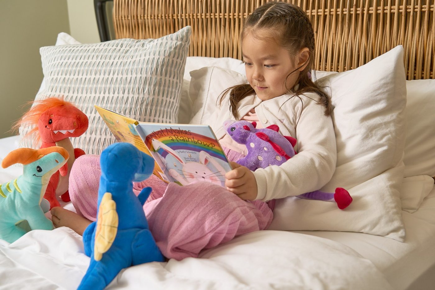 A child propped up in bed with an armful of plush animals