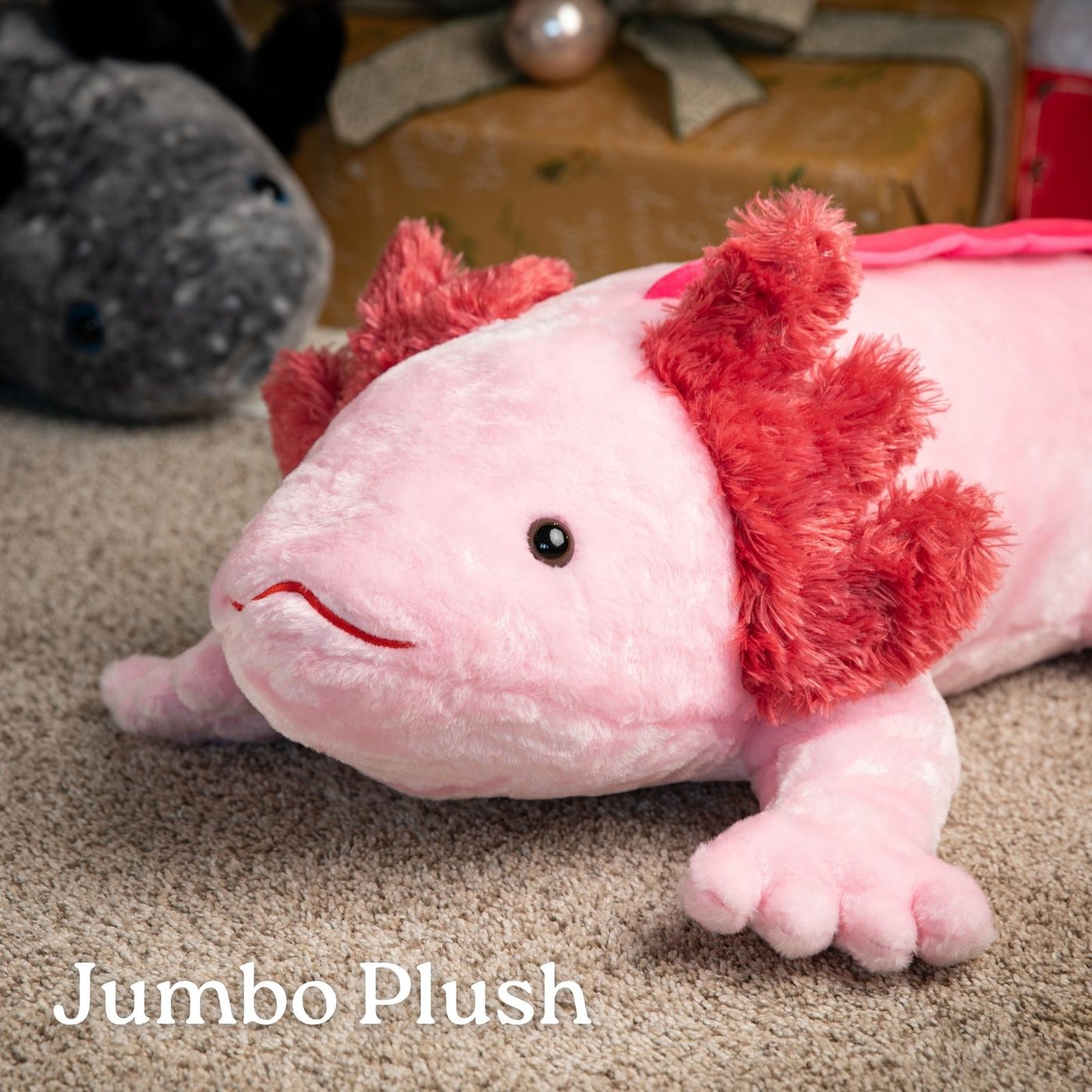 A giant pink axolotl jumbo plush toy on a carpet