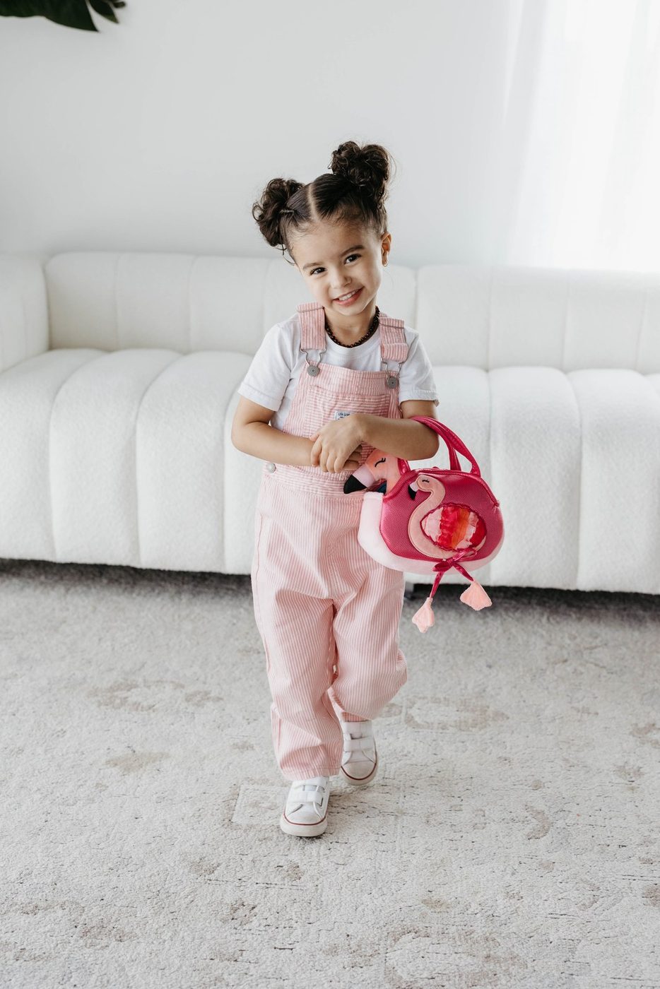 A girl in a tulle skirt carrying a small pink plush purse