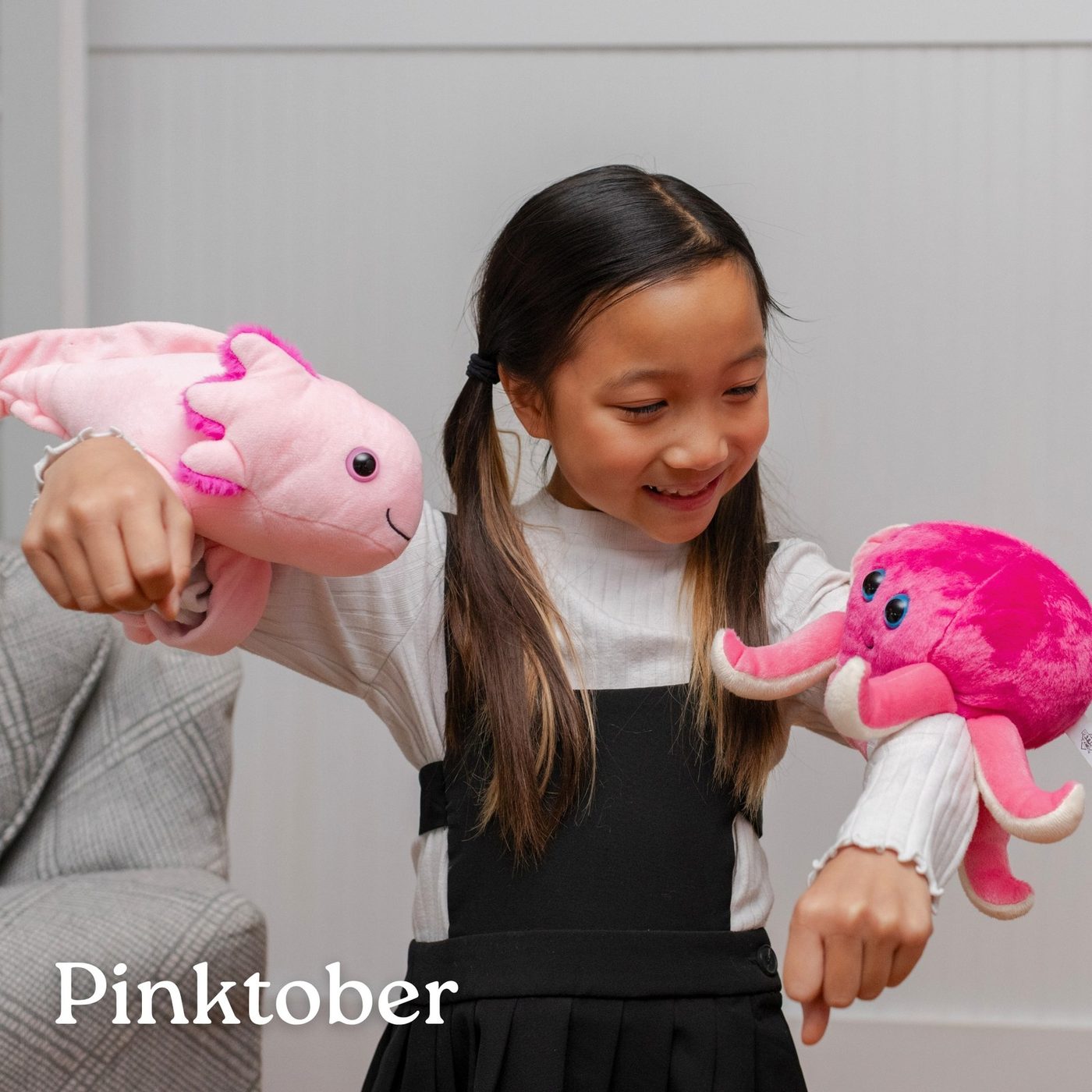 A girl holding a pink axolotl plush toy in each hand