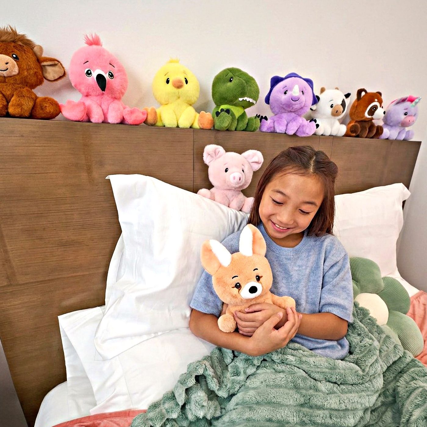 A girl in bed surrounded by a crowd of Zoologee plush animals
