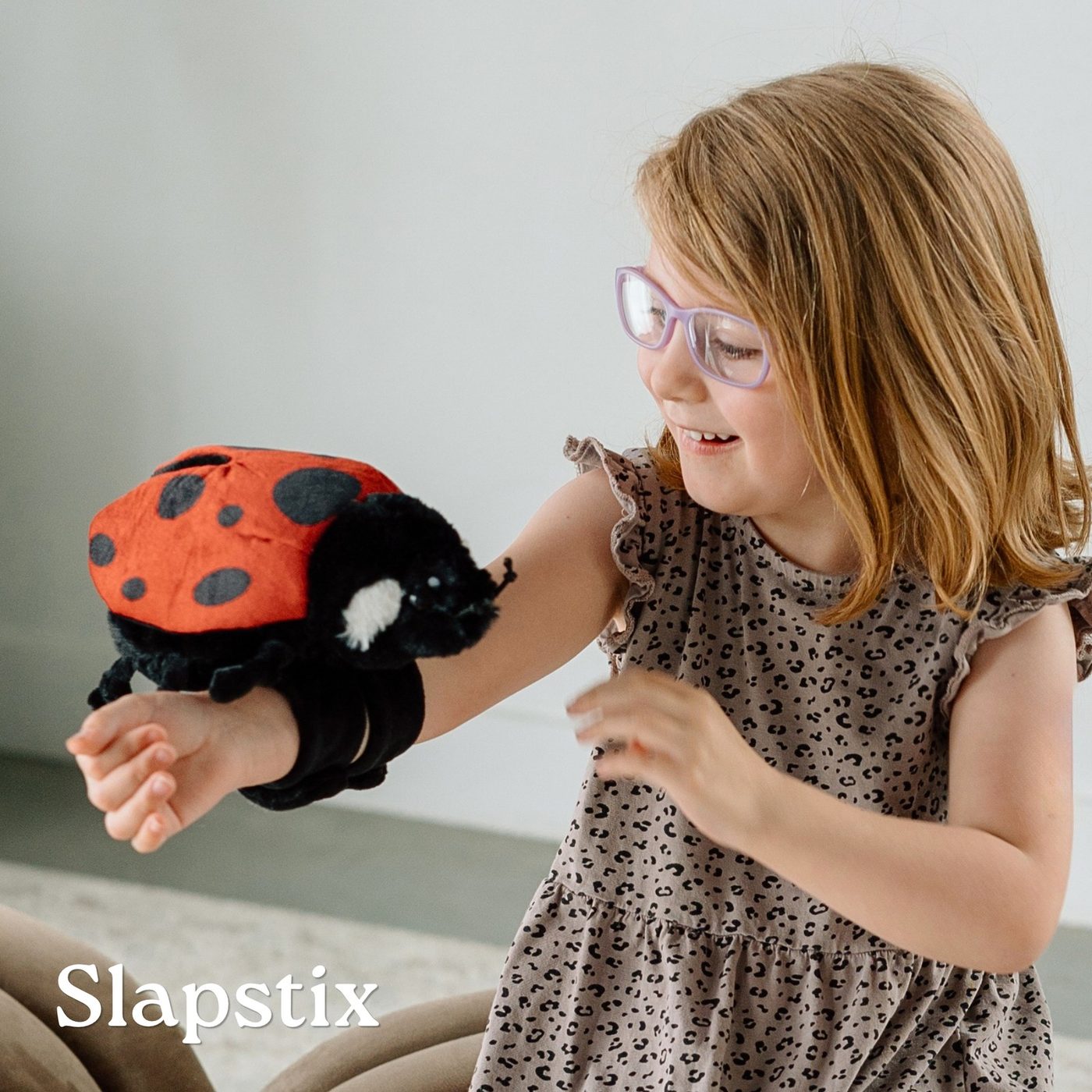 A girl wearing a ladybug Slapstix plush slap bracelet on her arm
