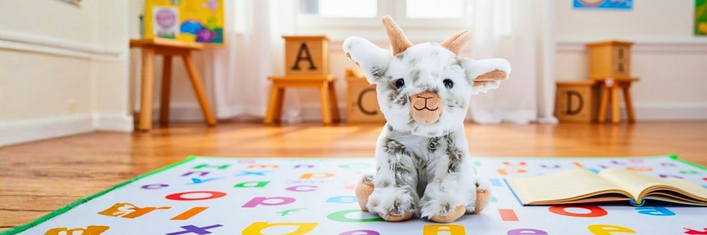 A grey bunny plush toy sitting on a colourful alphabet play rug