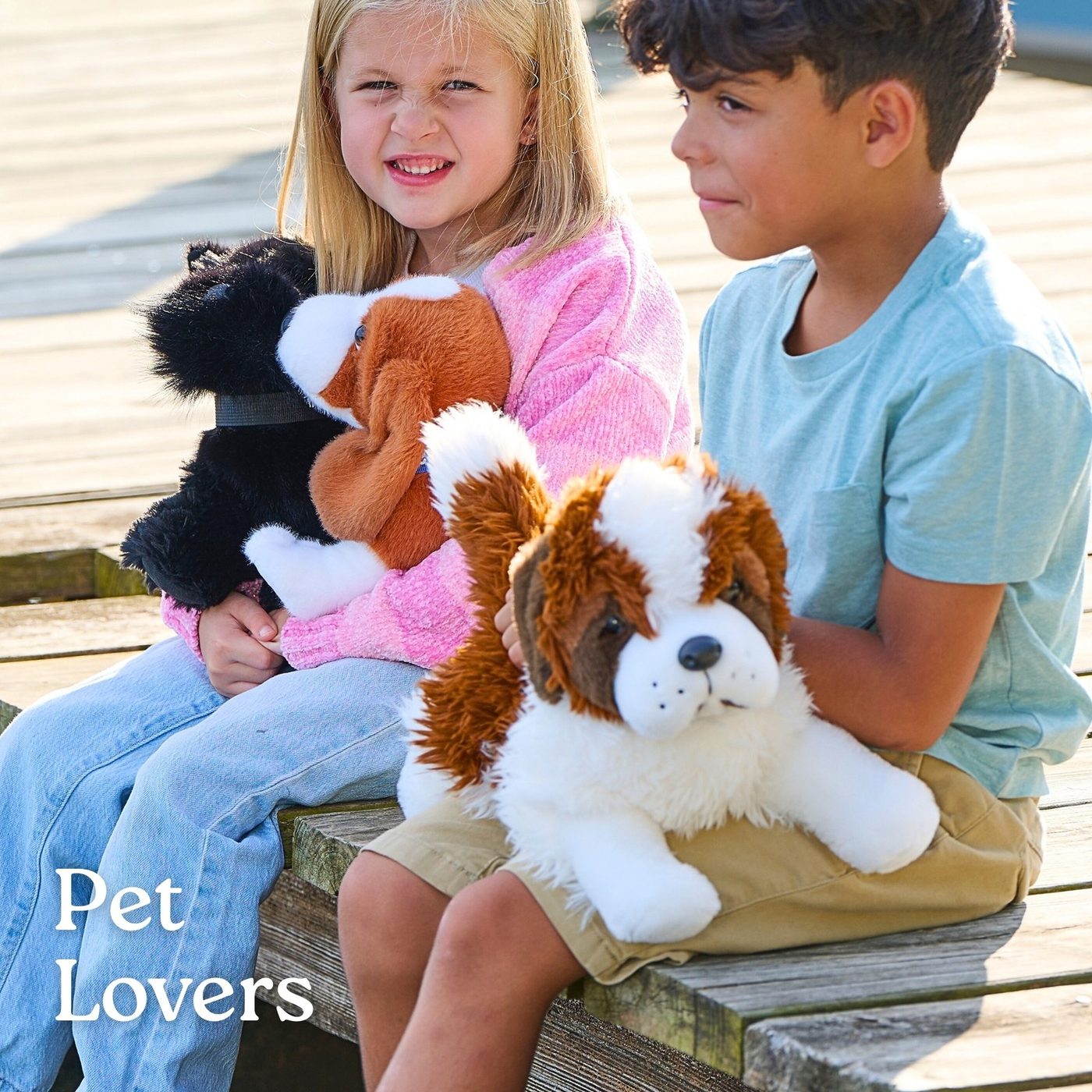 Two children sitting on a bench with spaniel and puppy plush toys